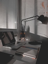 A cozy workspace with a laptop, notebook, and a small potted plant symbolizing growth and money.