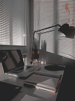 A bright workspace with plants and a notebook open beside a computer.