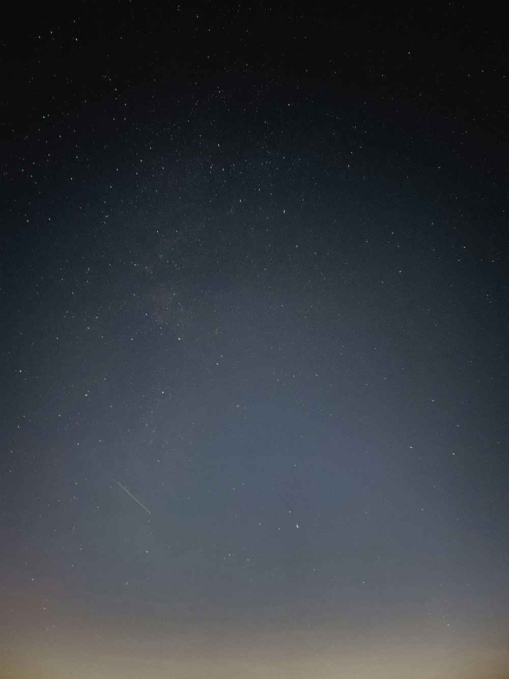 the night sky with stars and a plane in the distance