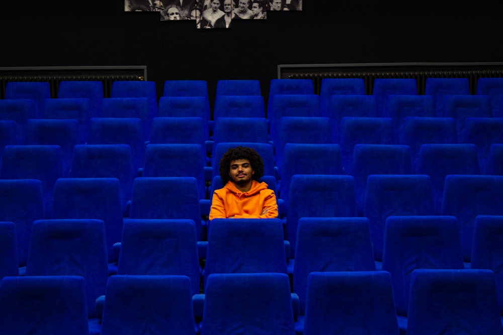 a man sitting in a blue chair in a theater