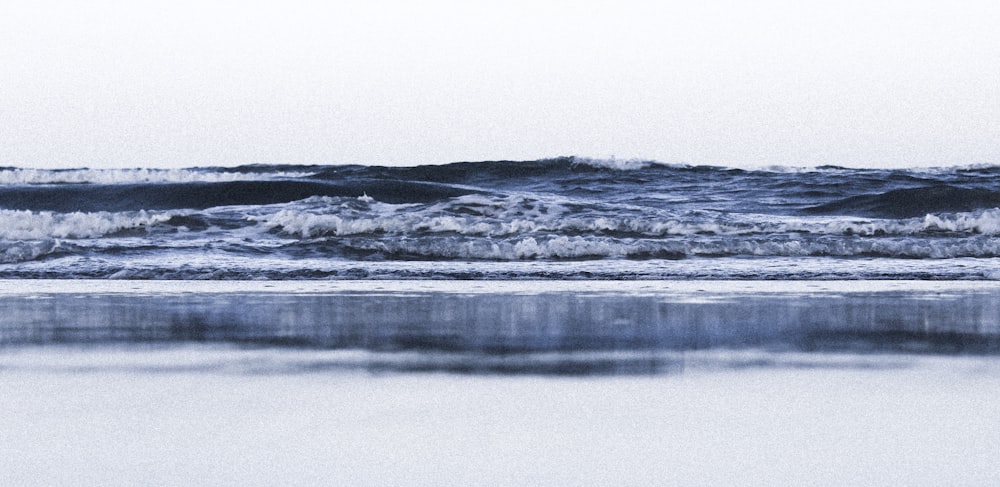 a person walking on a beach with a surfboard