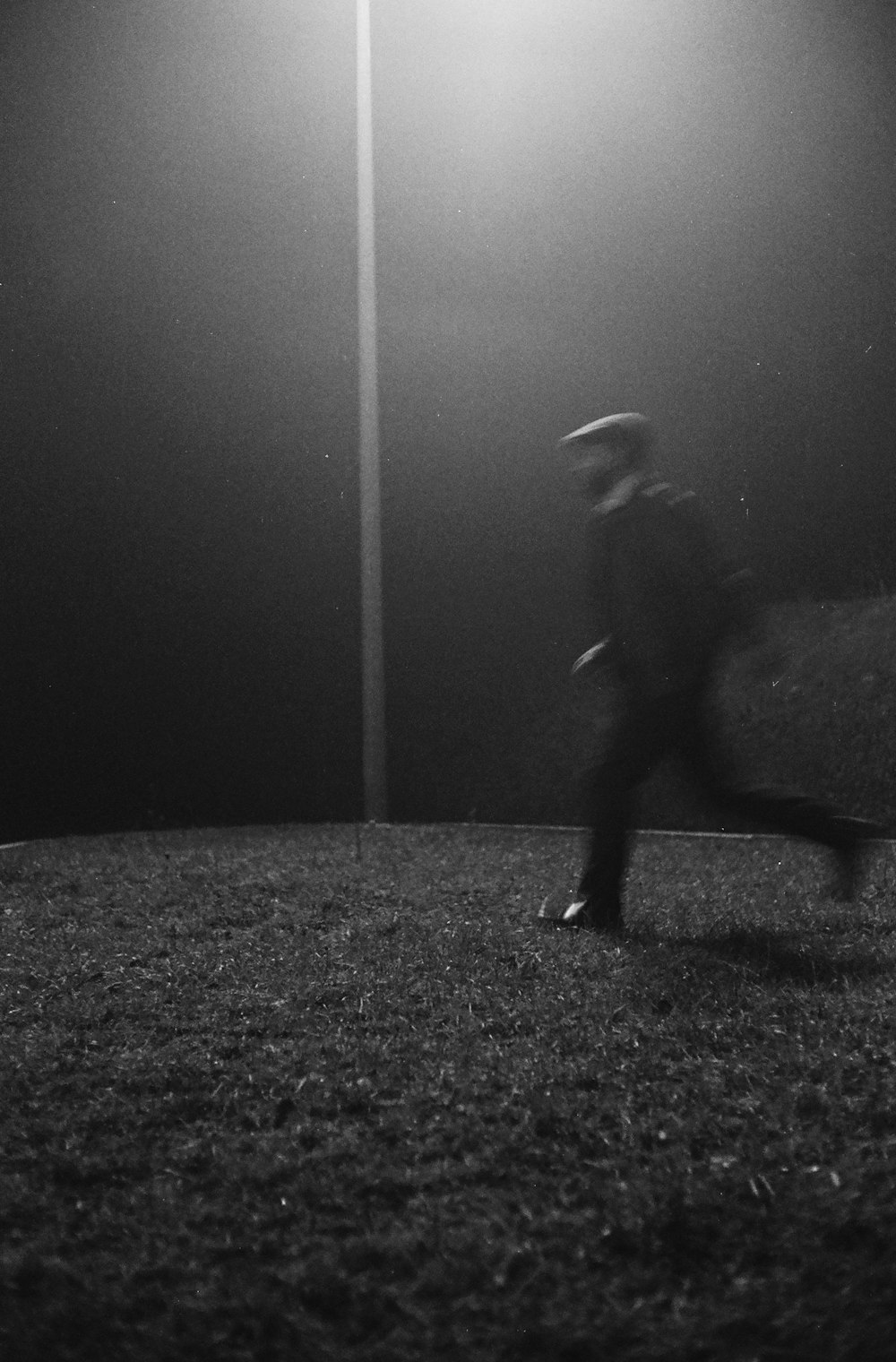a man walking across a field at night