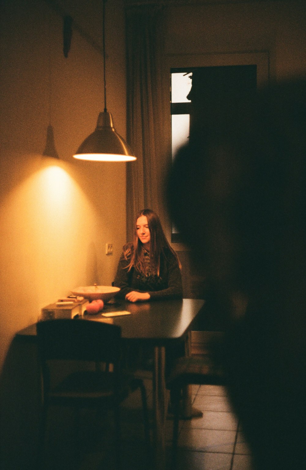 a woman sitting at a table in a dimly lit room