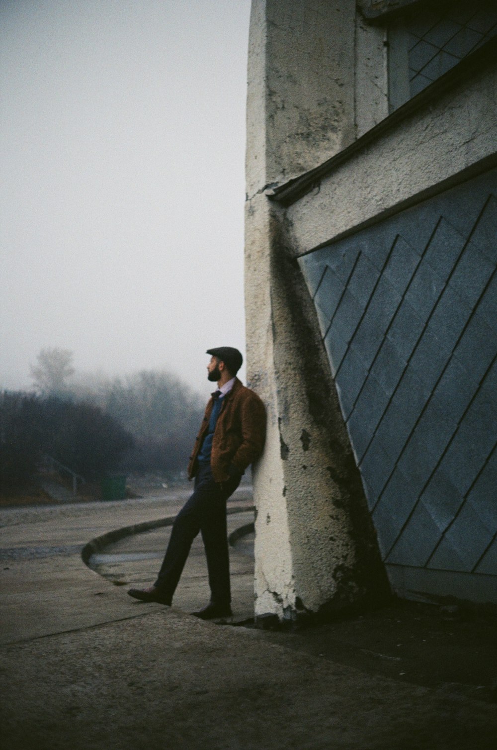 a man leaning against a building on a sidewalk