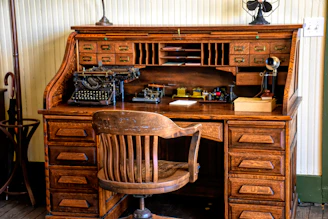A sturdy roll top desk with rich wood grain and classic brass handles.