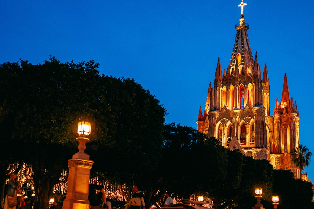 a large cathedral lit up at night with people walking around