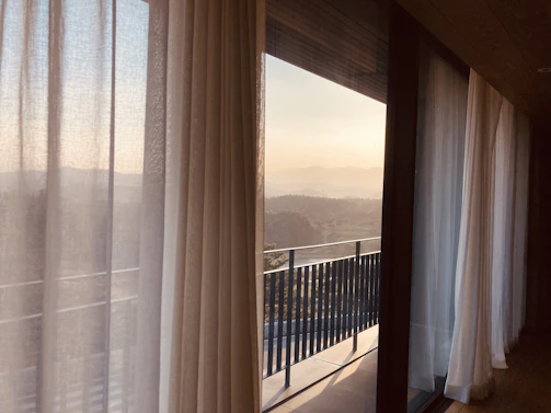Outdoor view of a balcony with SolarTek curtains providing shade and privacy during sunset.