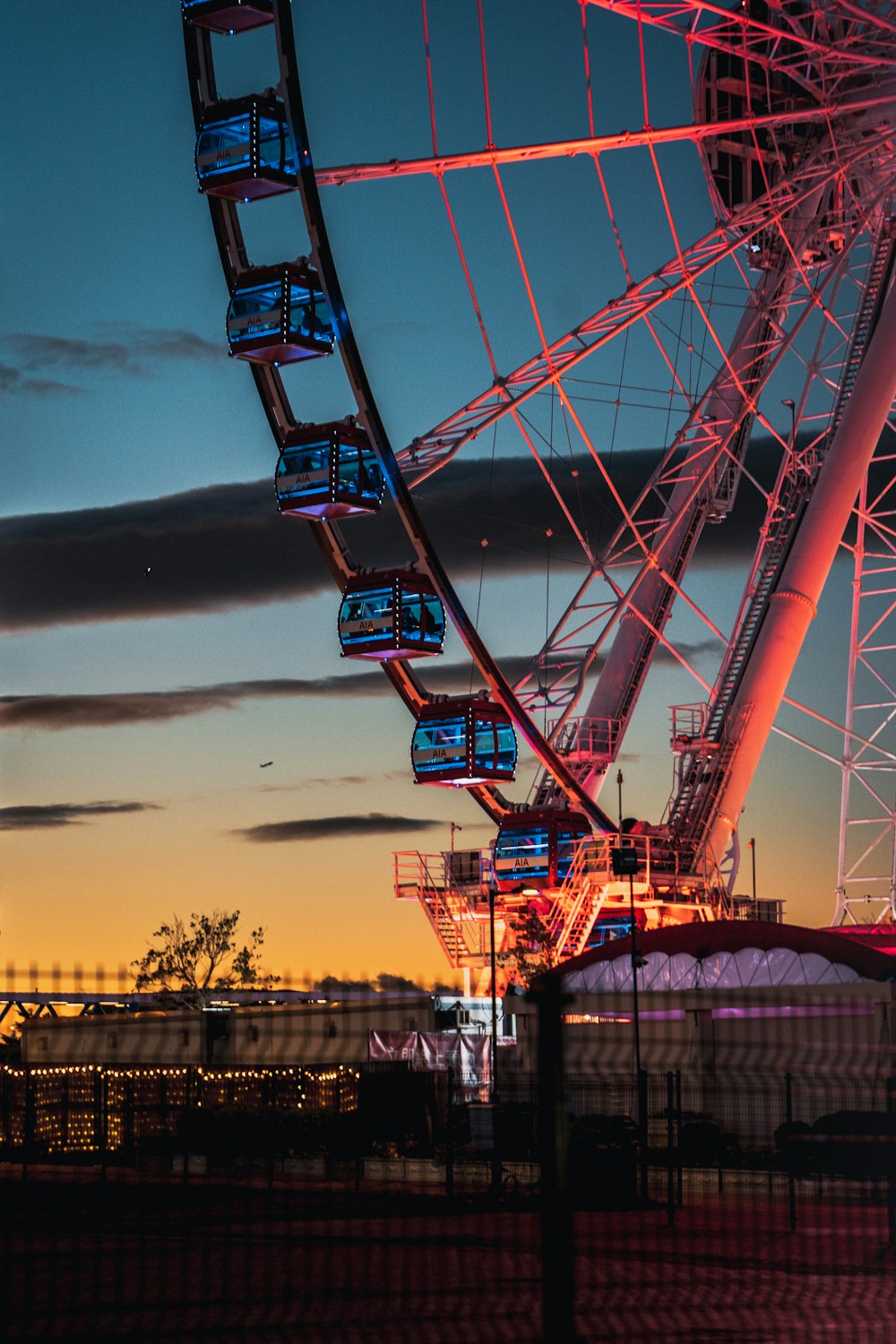 a ferris wheel lit up at night with the sky in the background