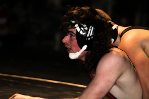 Two MMA fighters grappling on the mat with focused determination.