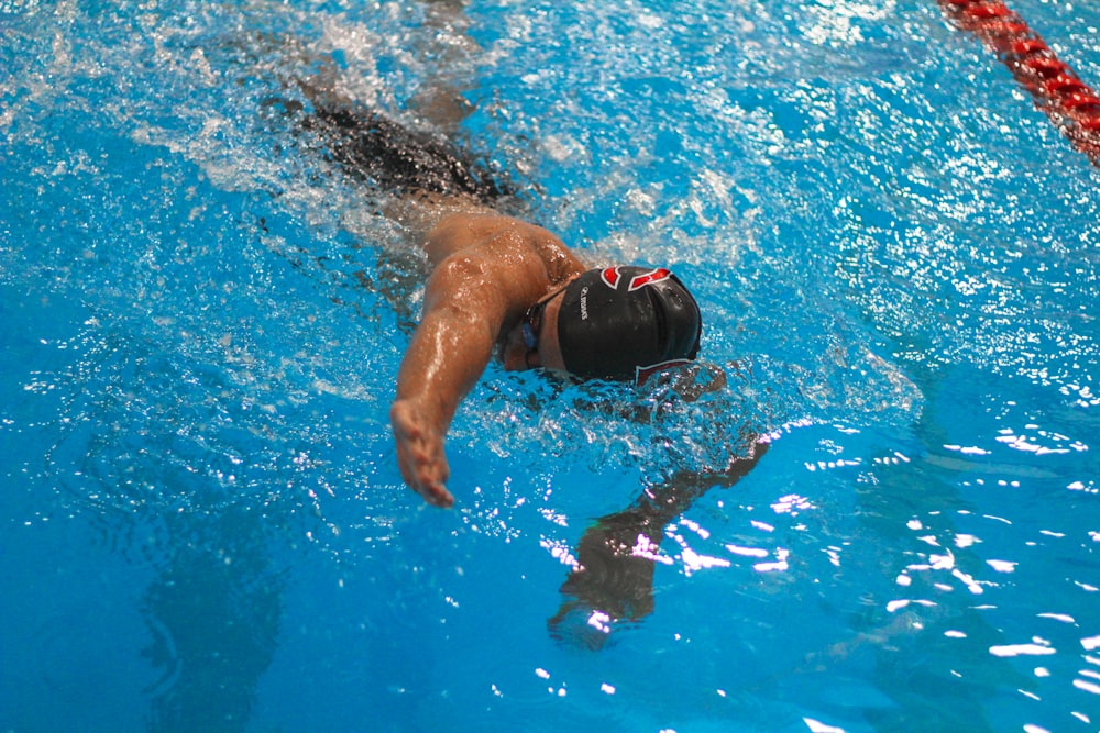 a man swimming in a pool with a hat on