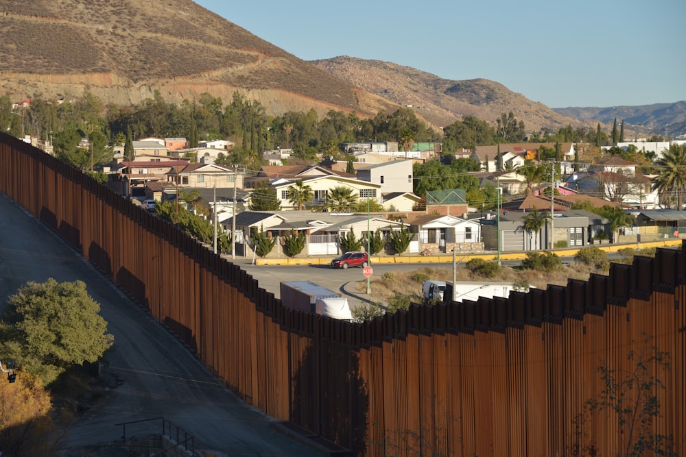 a section of the border fence with houses in the background