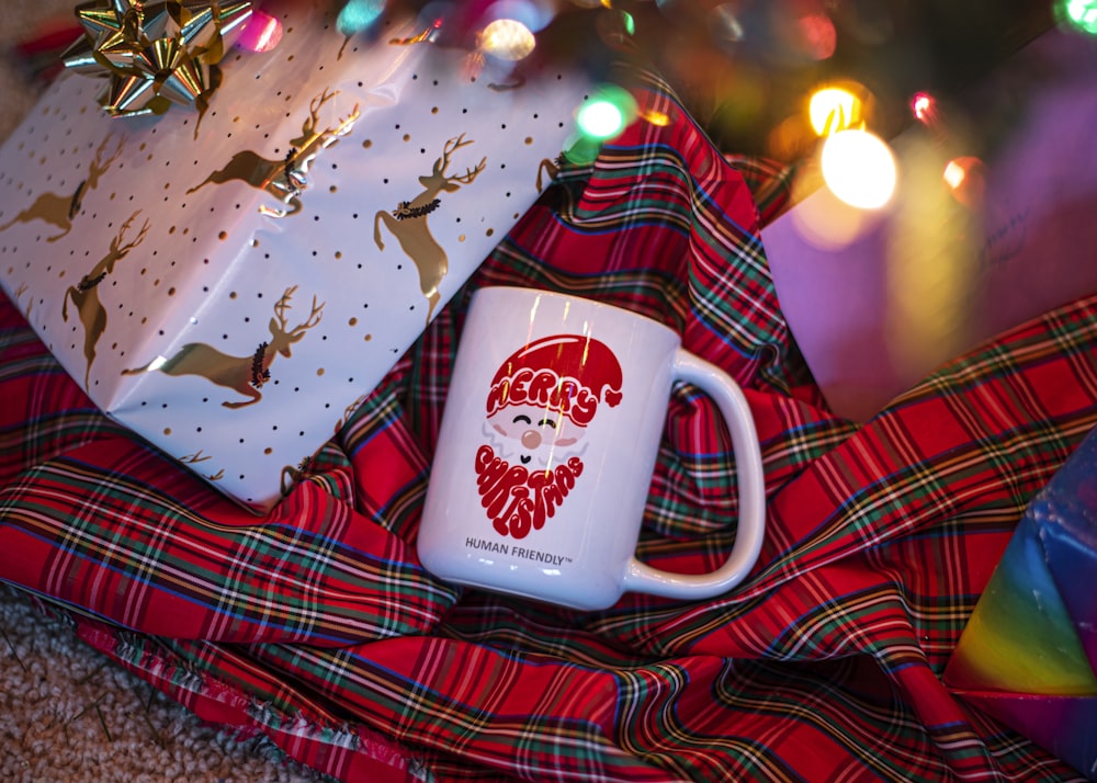 a white coffee mug sitting on top of a plaid blanket