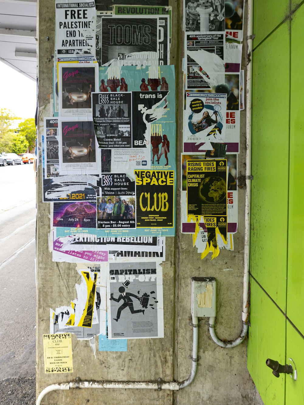 a wall covered in posters and papers next to a street