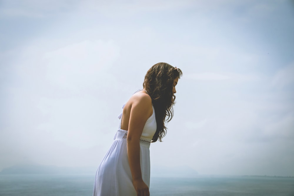 a woman in a white dress looking at the ocean