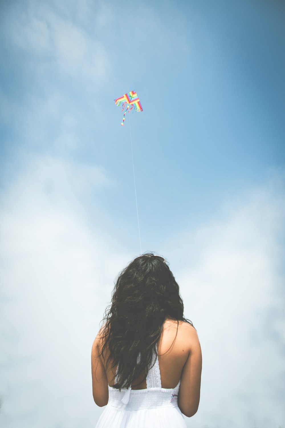 a woman in a white dress flying a kite