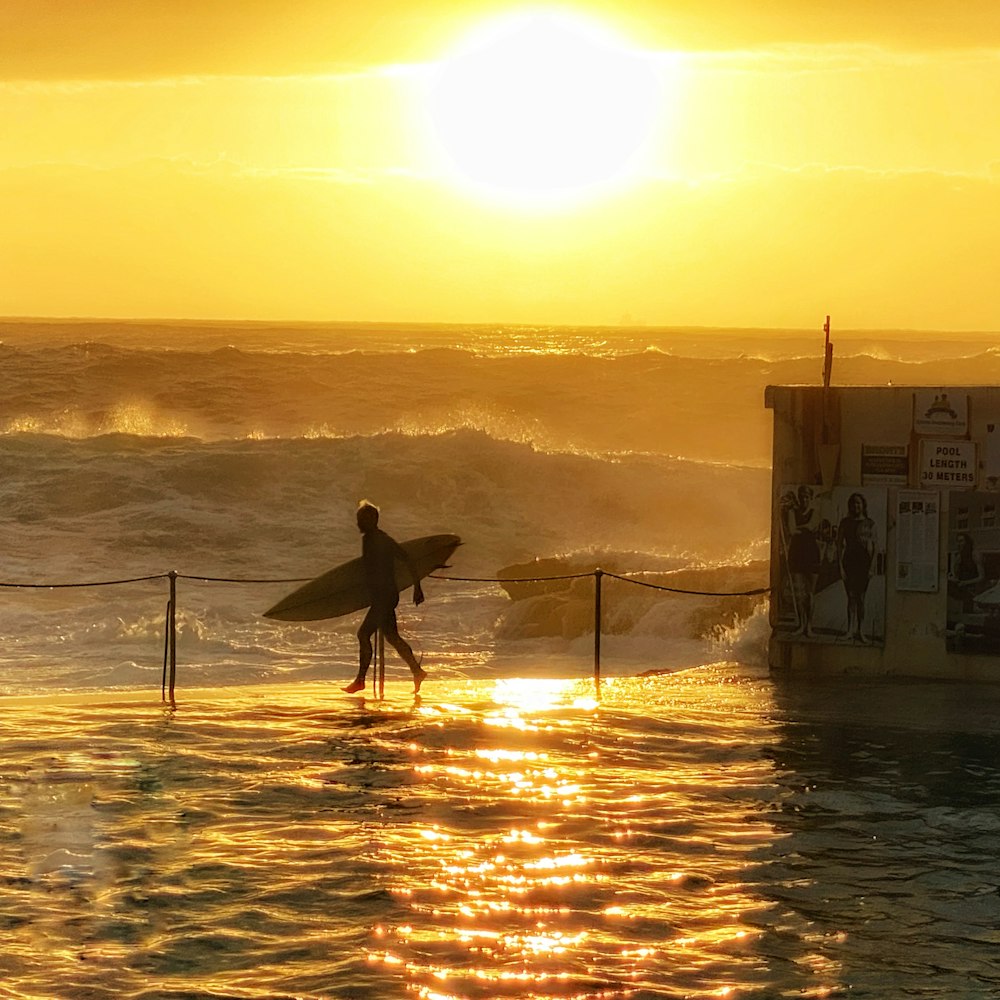 a man holding a surfboard walking into the ocean