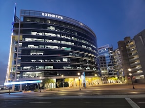 Modern office building exterior with dark tones and subtle yellow accents at dusk