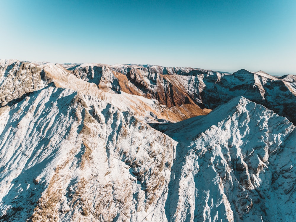 an aerial view of a mountain range with a blue sky