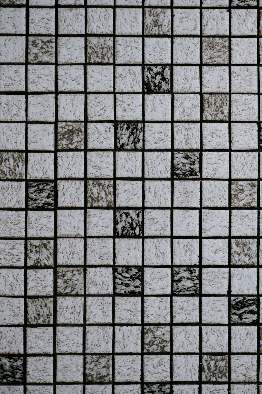 a close up of a tiled wall with black and white squares