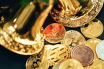 A collection of various cryptocurrency coins are scattered, including prominent ones like Ethereum and Bitcoin, surrounded by decorative golden objects.