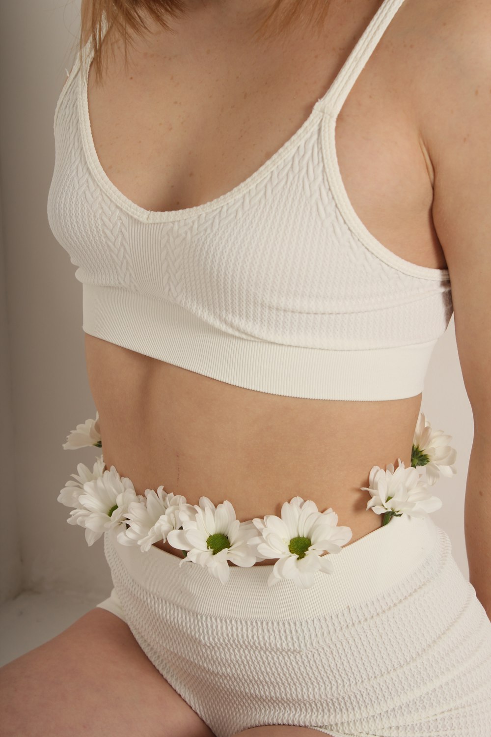 a woman wearing a white top and flower belt