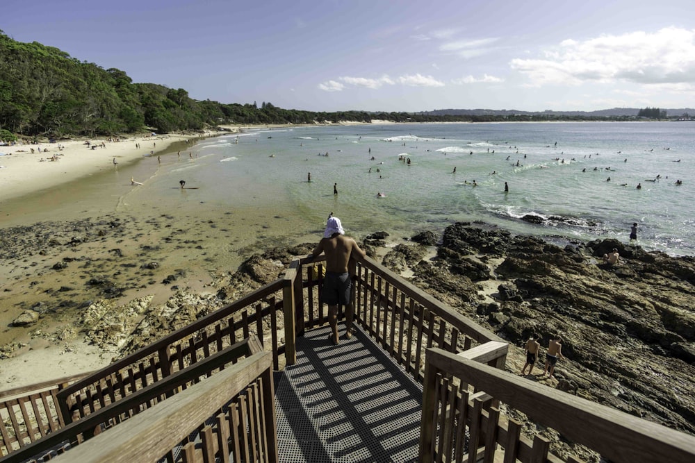 uma pessoa em pé em um corrimão olhando para a praia