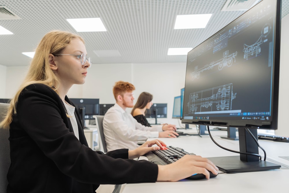 a woman sitting in front of a computer monitor