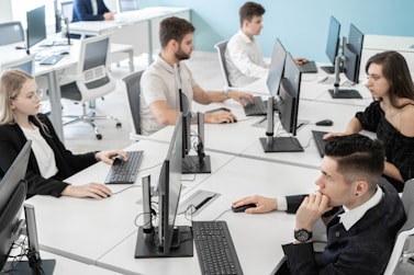 a group of people sitting at a table with computers