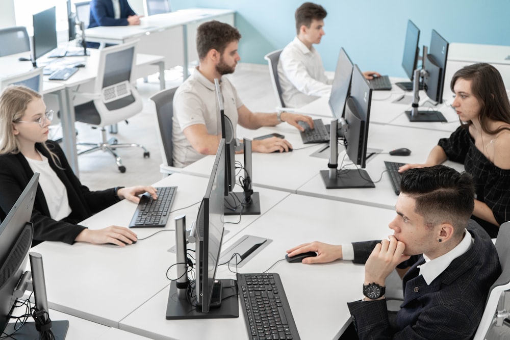 a group of people sitting at a table with computers