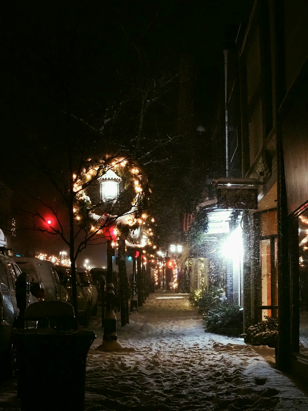 a snowy street at night with lights and a wreath