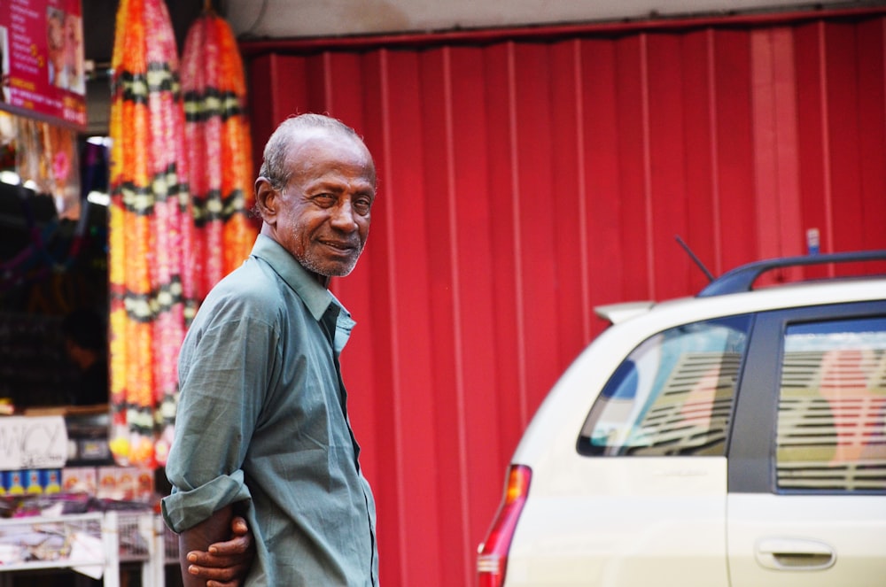 a man standing next to a white car in front of a red building