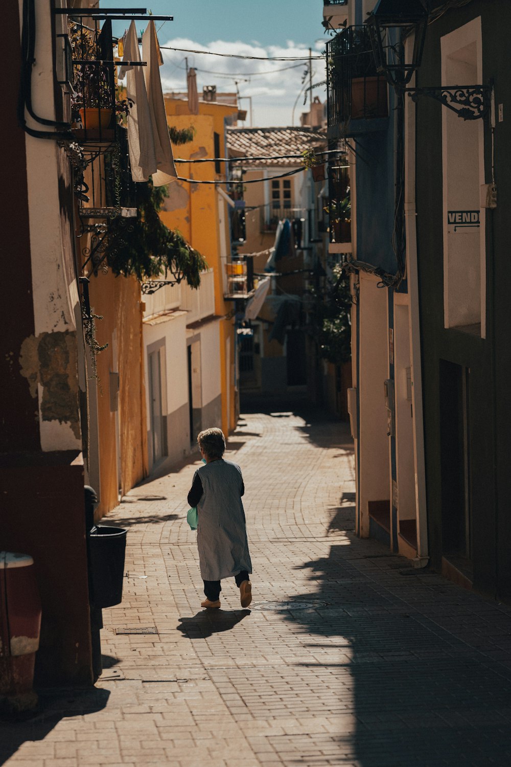 a woman walking down a street next to tall buildings