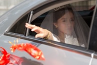 A professional chauffeur assisting a bride and groom.