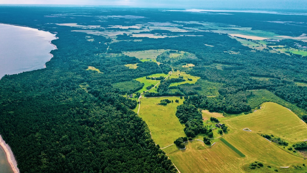 an aerial view of a lush green field next to a body of water