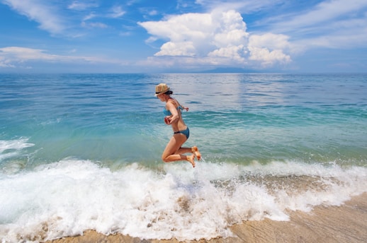 a woman in a bikini jumping into the ocean