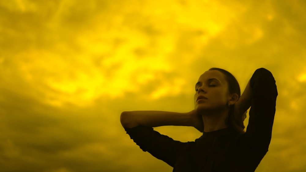 a woman standing in front of a yellow sky