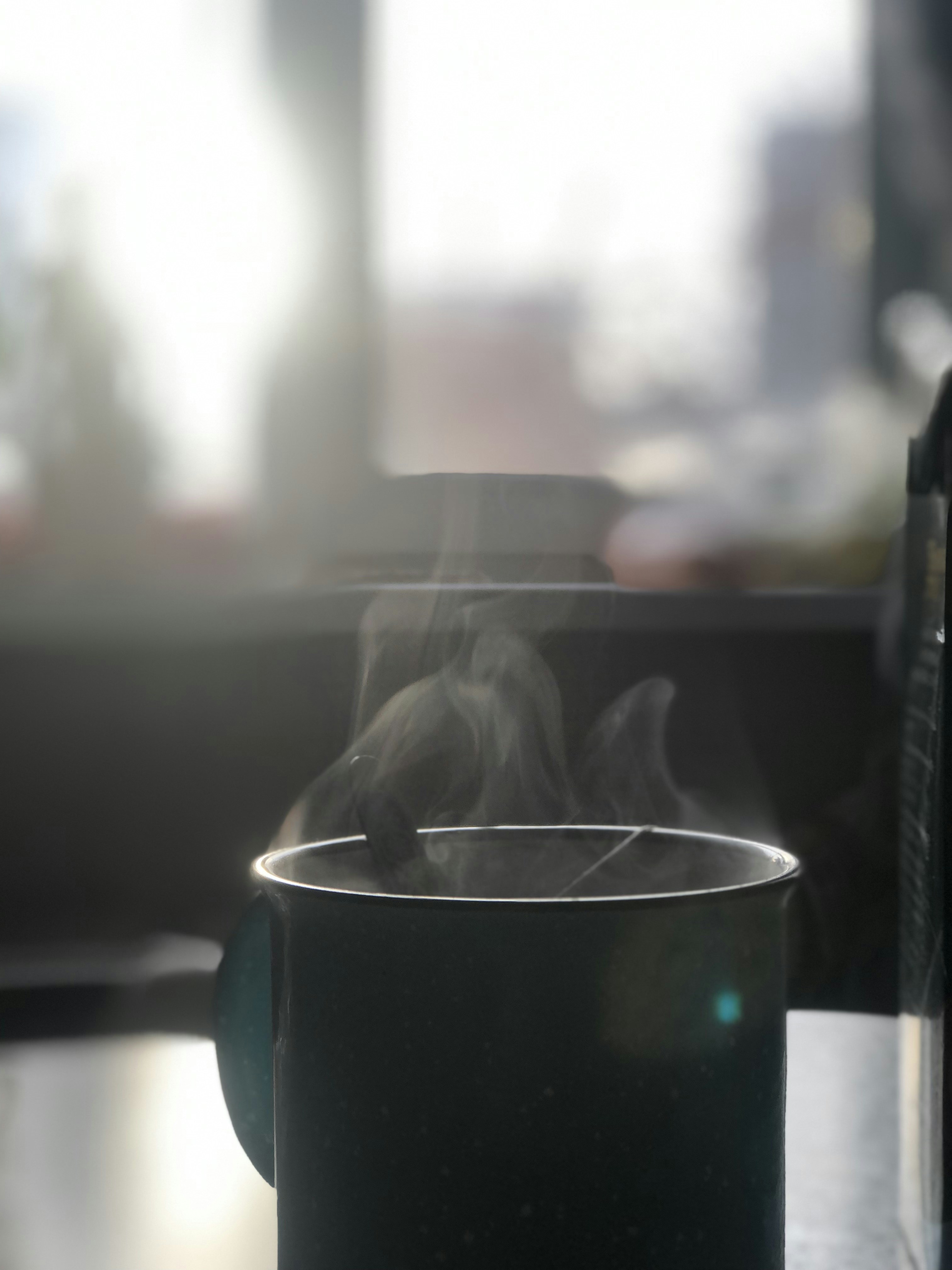 a steaming cup on a table next to a bottle of wine