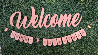 Wooden signage with elegant lettering used as a welcome sign at an outdoor celebration.
