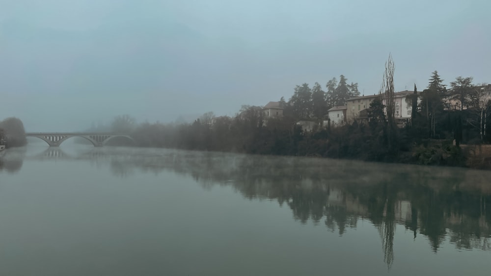 a foggy river with a bridge in the distance