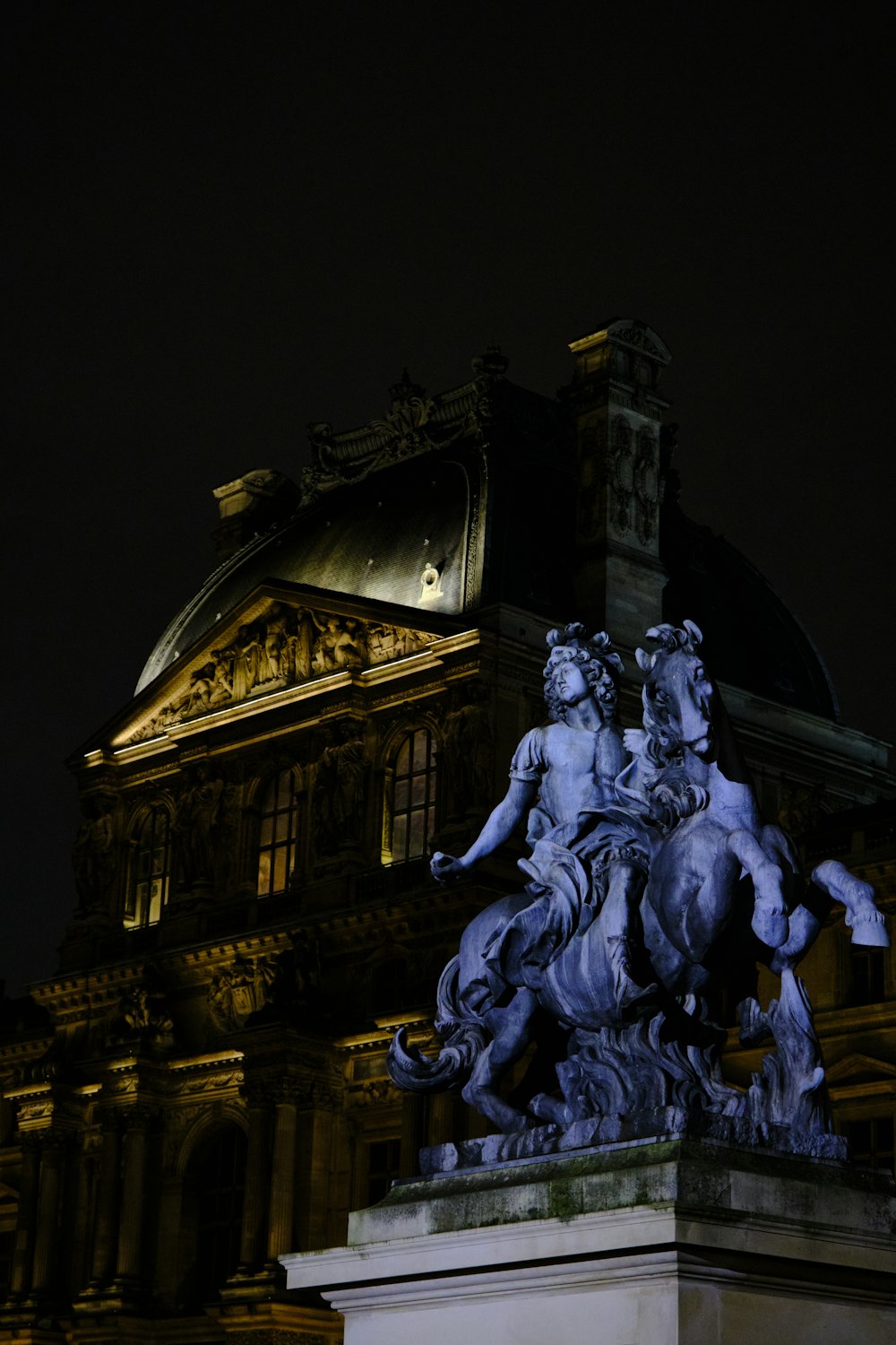 uma estátua de um homem montando um cavalo na frente de um edifício