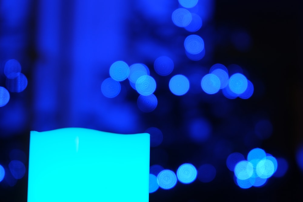 a lit candle in front of a blue background