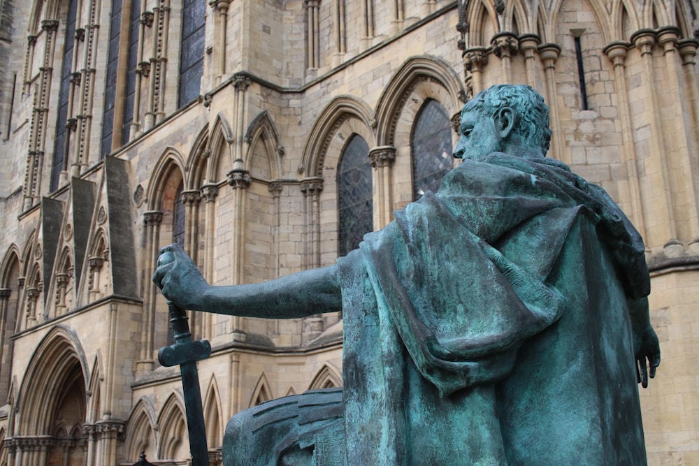 a statue of a man holding a cane in front of a building