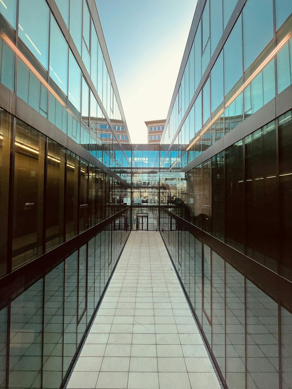 an empty walkway between two buildings with glass walls