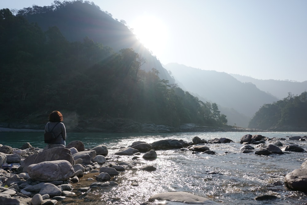 a person sitting on a rock near a river