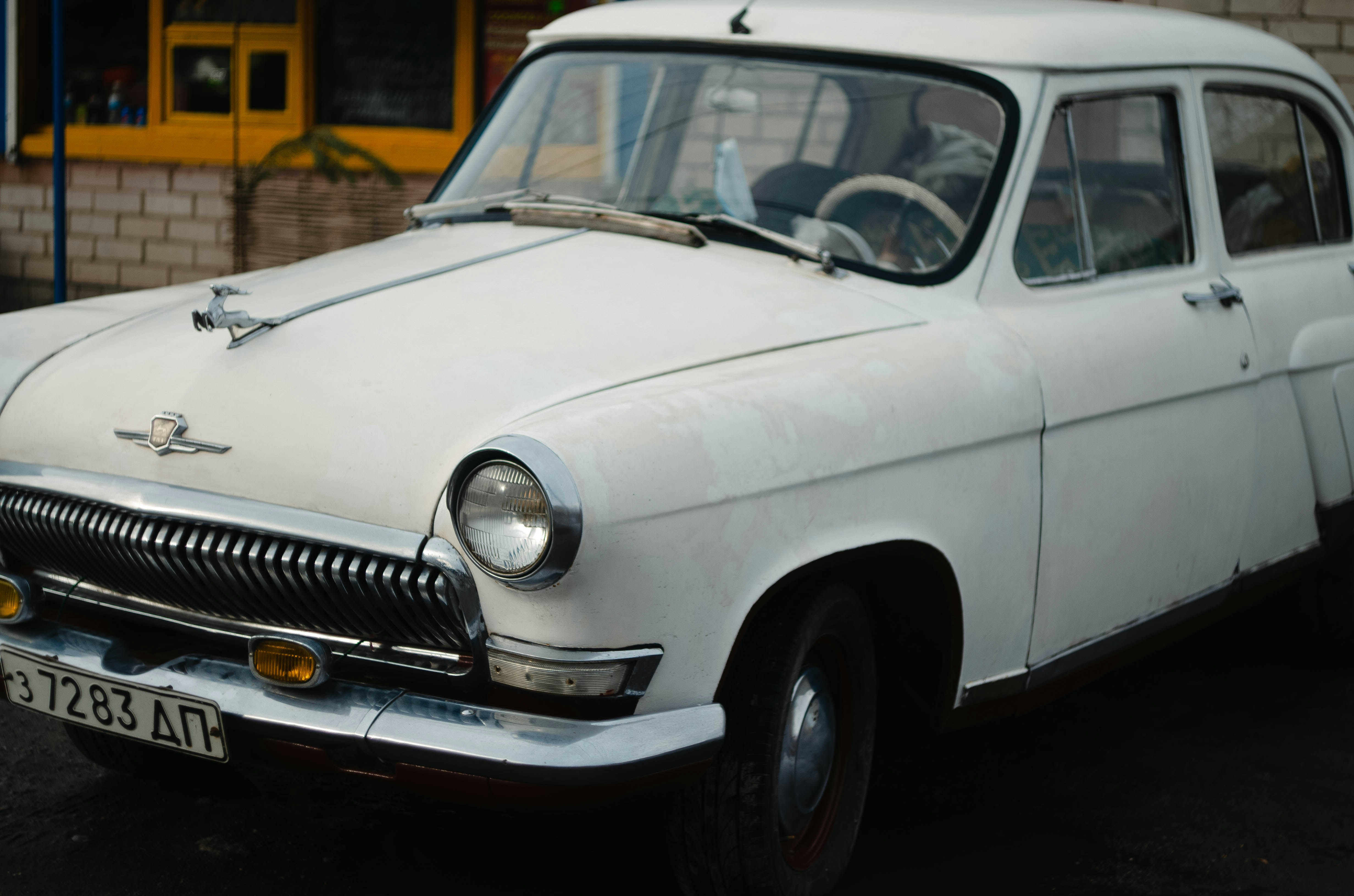 an old white car parked in front of a building