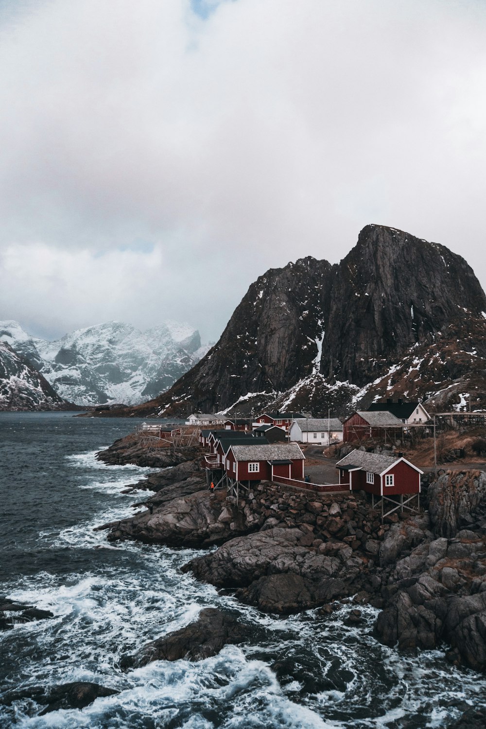 a house on a rocky shore with a mountain in the background