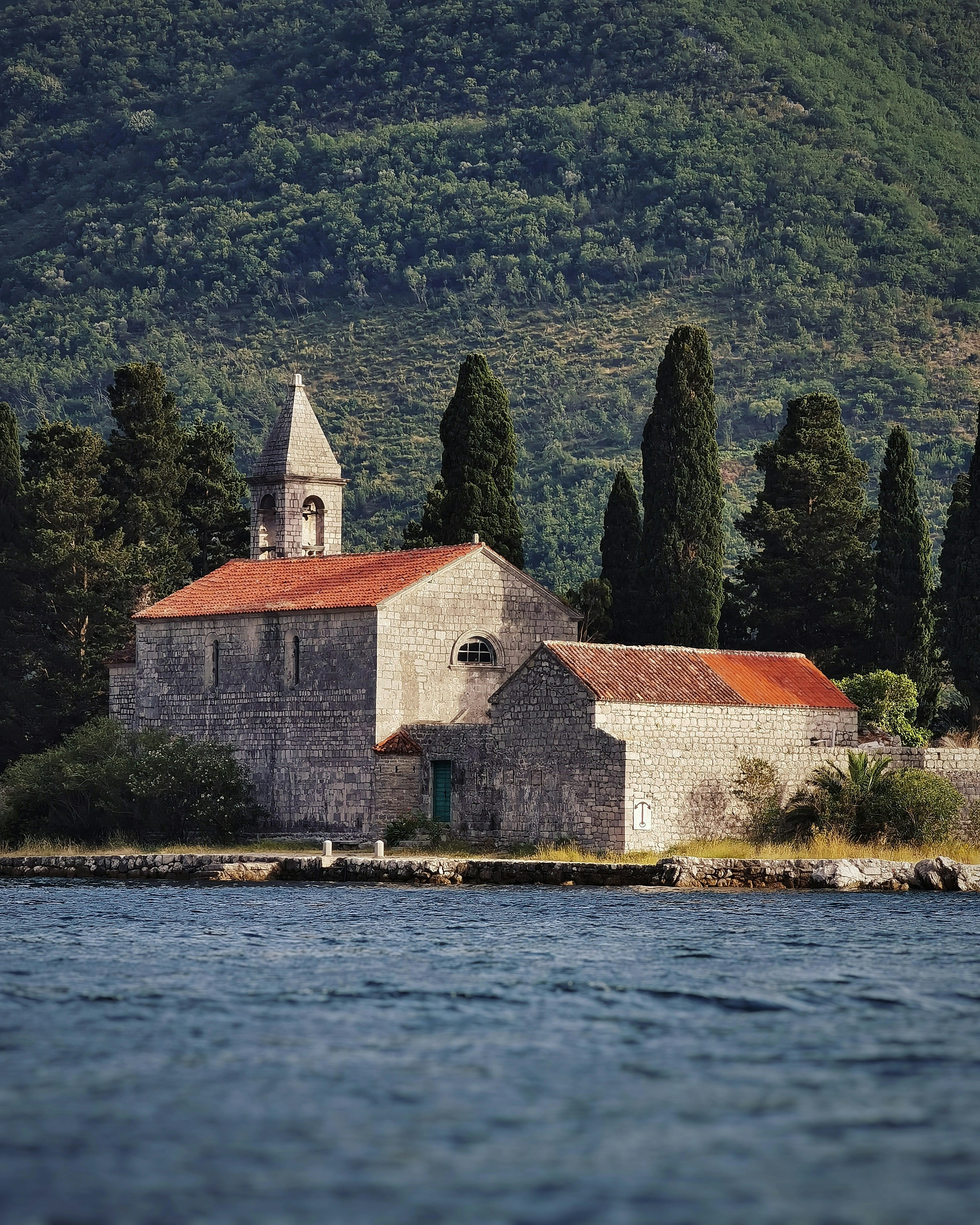 an old church sits on the shore of a lake