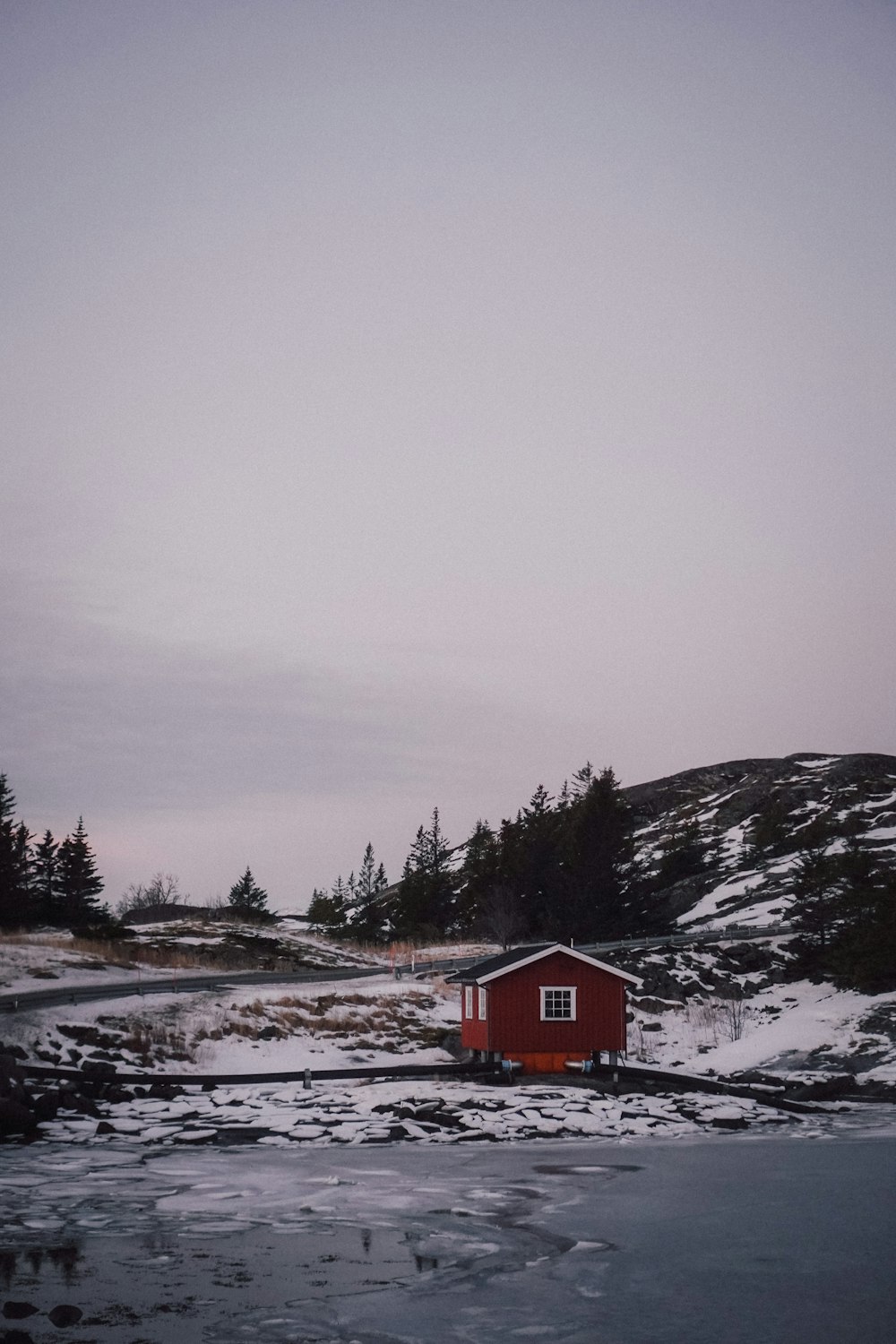 a small red house sitting on top of a snow covered field