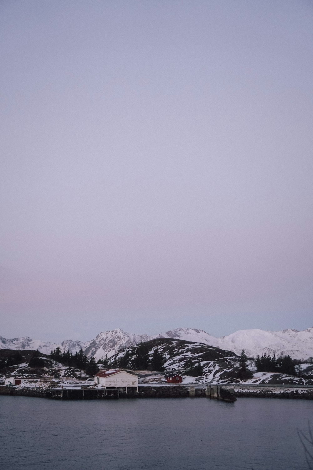 a body of water with snow covered mountains in the background