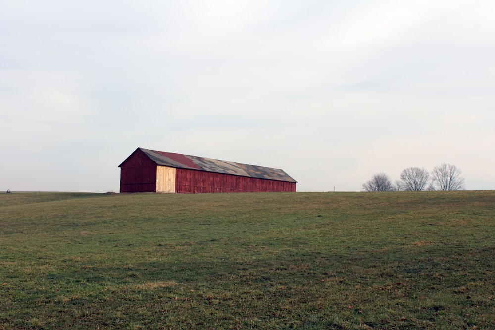 a red barn in the middle of a grassy field